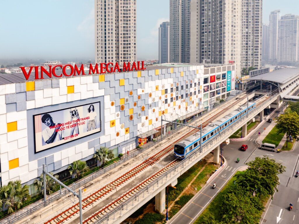 Mặt ngoài Vincom Mega Mall Thảo Điền với tàu metro trên đường ray phía trước
